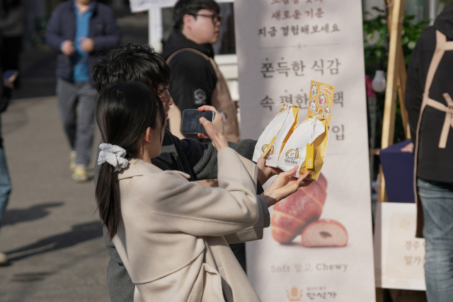 갓구운 찰보리소금빵을 들고 인증 사진을 찍는 방문객들