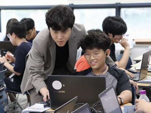 ‘신한 AI크리에이터 캠프’에 참여한 강사가 학생의 프로젝트 진행 상황을 살펴보며 조언하고 있다