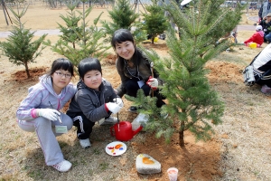 - 소아암 어린이 가족이 희망나무를 심은 후, 이름돌을 꾸미고 있다.
