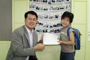 한국백혈병어린이재단 서선원 사무국장(왼쪽)이 오지성 어린이(오른쪽)에게 6년동안 기른 머리