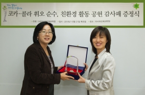 (사)아시아인재과학원 이영숙 이사가 한국 코카-콜라 박형재 상무에게 친환경 활동 공헌에 대