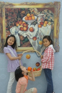 어린이들이 세잔의 사과와 오렌지 패러디에서 떨어지는 사과를 들고 먹는 시늉을하며 즐거워하고