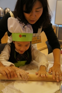 큐원 키즈 쿠킹클래스에 참가한 아이가 엄마와 함께 케익을 만들며 즐거운 시간을 보내고 있다