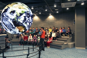 우주과학 캠프에 참가한 청소년이 SOS에 투영된 지구를 흥미롭게 바라보고 있다