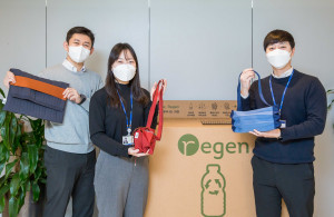 효성티앤씨 직원들이 사내 페트병 수거함 앞에서 친환경 섬유 리젠으로 만든 가방을 선보이고 